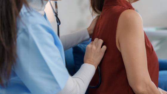doctor using stethoscope examining lungs of senior patient