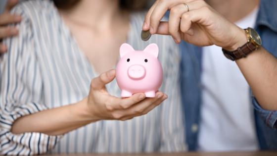 Couple putting coins into piggy bank