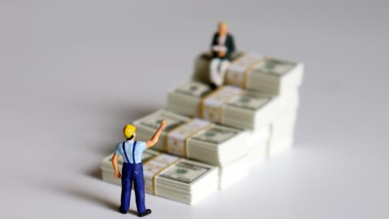 Miniature people with banknotes in the shape of a staircase.