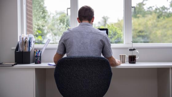 Rear View Of Man Working From Home On Computer In Home Office
