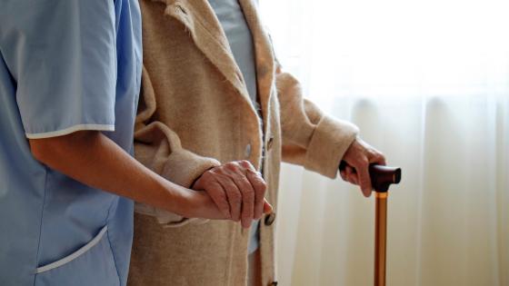 Senior woman holding quad cane handle in elderly care facility