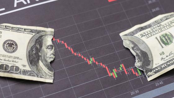 Torn dollar bill on top of negative financial chart