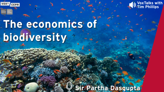 Graphic promoting a VoxTalks interview with Sir Partha Dasgupta titled “The economics of biodiversity”, featuring a vibrant coral reef teeming with colourful fish and marine life.